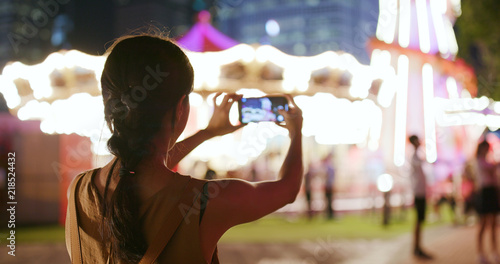 Canvas Print Woman taking photo and video in amusement park at night