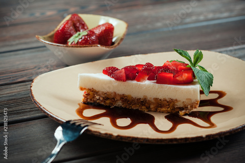 Slice of strawberry yogurt or coconut cake decorated with fresh fruits and mint on a plate. Delicious and sweet pink cake for Valentines or birthday party. Homemade bakery concept. Selective focus