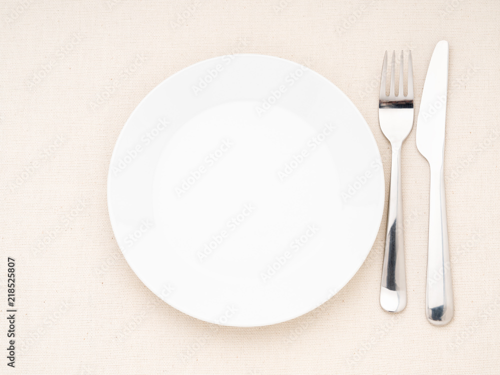 Blank flat plate, fork, knife on white table, top view. Mock up, copy space Blank flat plate, fork, knife on white table, top view. Mock up, copy space