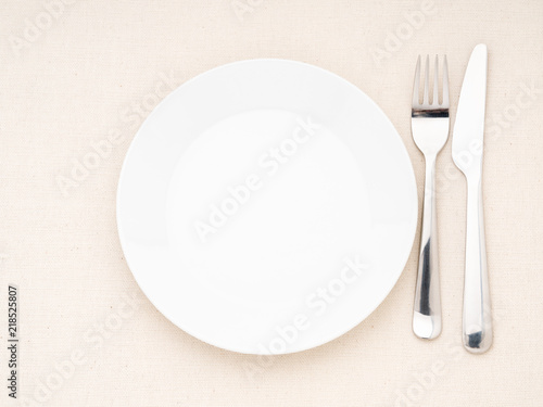 Blank flat plate, fork, knife on white table, top view. Mock up, copy space