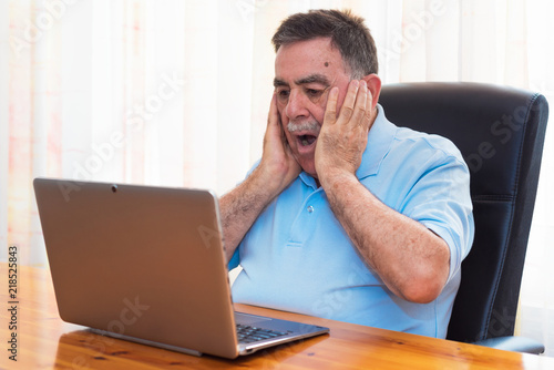 Surprised Senior man working with laptop.