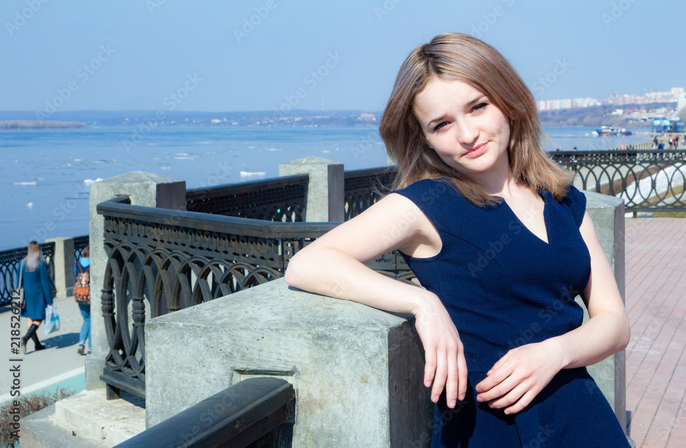 A young  woman  a blue top on the city waterfront on a summer day