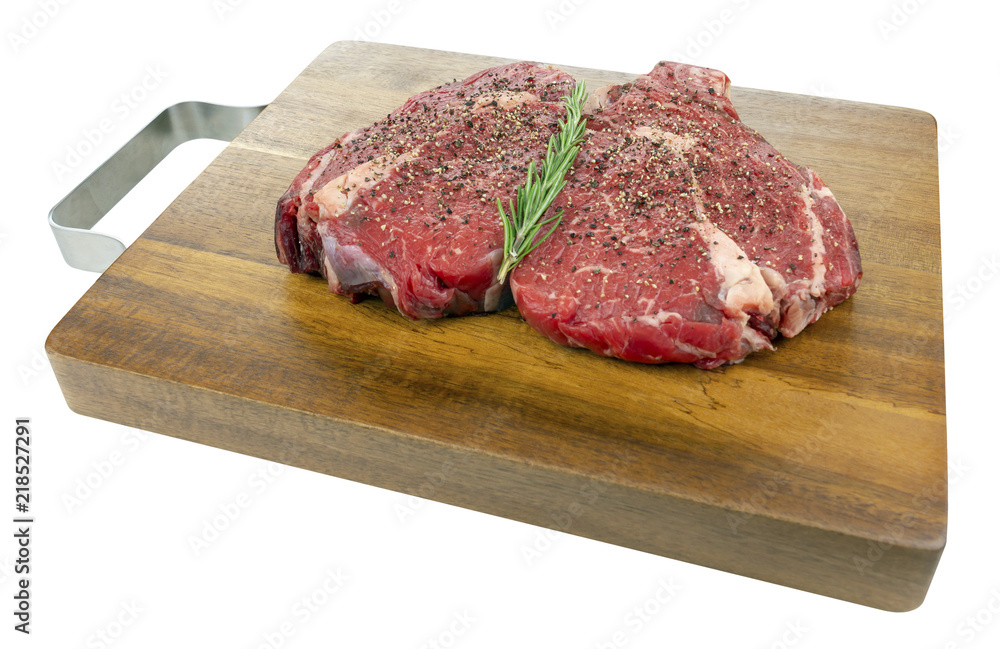 Fototapeta premium Peppered Raw Rib Eye Steaks on a Wooden Board Isolated