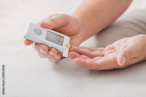 Фотография man measures sugar level with a glucometer