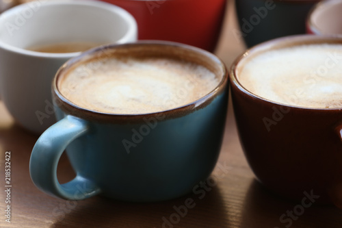 Cups of fresh aromatic coffee on wooden table, closeup