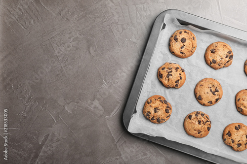 Schilderij op canvas Baking sheet with chocolate chip cookies and space for text on grey background,