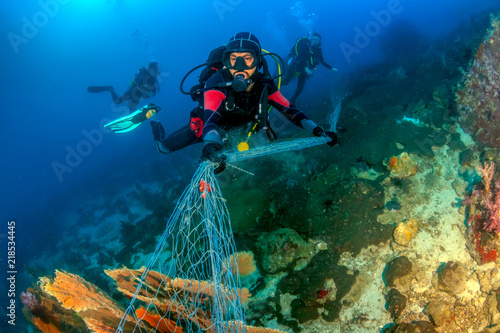 Fotografie SCUBA divers attempting to remove a huge ghost fishing net tangled over a large