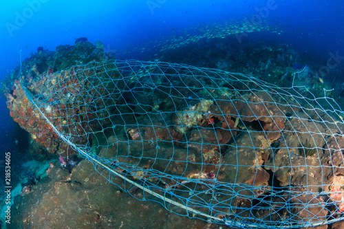 A huge abandoned ghost fishing net entangled over a large part of a tropical coral reef