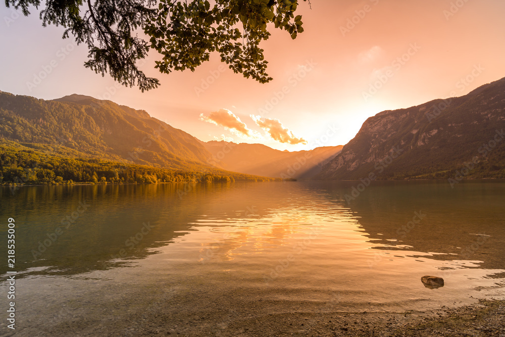 Obraz premium Sunset above the Bohinj lake, Slovenia. Magical evening color of sun with reflection in water. Julian Alps in background. Triglav national park