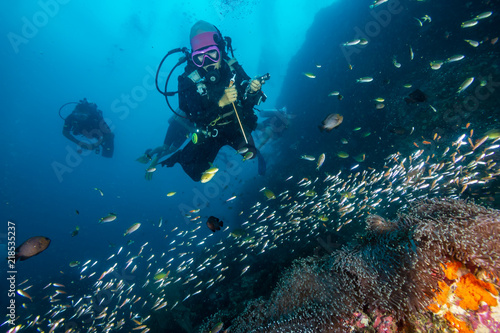 Female SCUBA diver exploring a dark, tropical coral reef