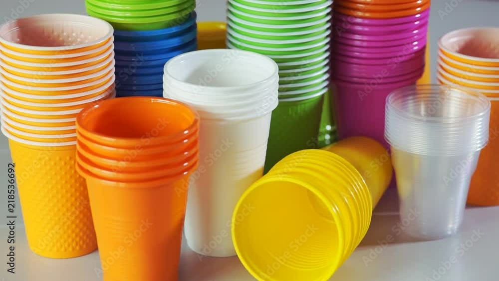 Disposable cups. Stack of colorful plastic cups on the table. Rotation. Closeup Disposable cups. Stack of colorful plastic cups on the table. Rotation. Closeup