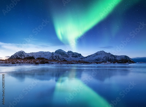 Aurora borealis on the Lofoten islands, Norway. Green northern lights above mountains. Night sky with polar lights. Night winter landscape with aurora and reflection on the water surface. © biletskiyevgeniy.com