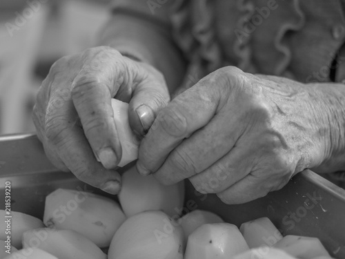 Old, hands are peeling potatoes photo
