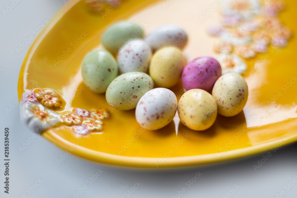 Colorful chocolate Eater eggs on a yellow plate Colorful chocolate Eater eggs on a yellow plate