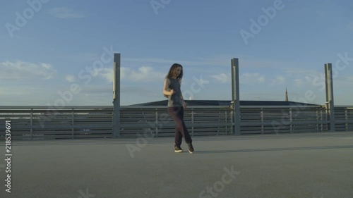 female Dancer walks into the frame, dancing hip hop on a concrete envoirenment  photo