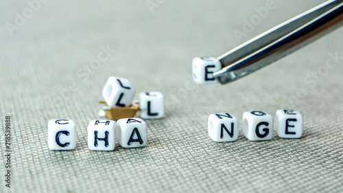 Removing white cubes with a tweezer with letters l and e of the word challenge creating new word change on grey background with miniature figurines photo
