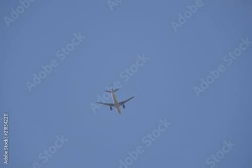 A airplane flies through the blue and cloudless sky.