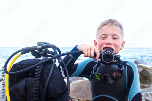 cheerful boy with blond hair breathes through a diving balloon