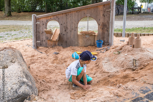 Junge mit Cap spielt in Sand in Sandkasten Spielplatz