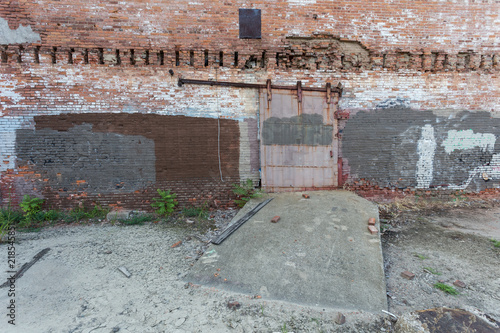 Fototapeta Naklejka Na Ścianę i Meble -  Abandoned lot with large industrial metal door on rail