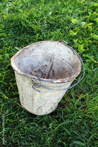 Old rusty bucket on the green grass