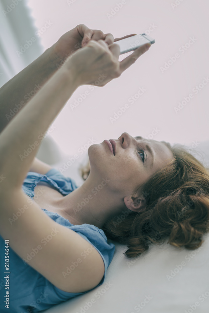 Naklejka premium young redhead beauty smiling with smartphone 