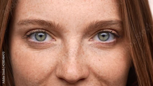 Extreme closeup portrait of lovely european woman 20s with ginger hair and freckle looking on you with happy smile, isolated over white background. Concept of emotions