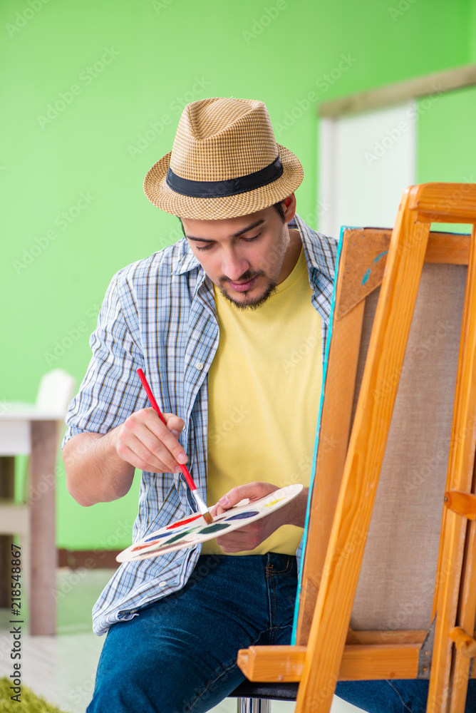 Young male artist working on new painting in his studio Young male artist working on new painting in his studio