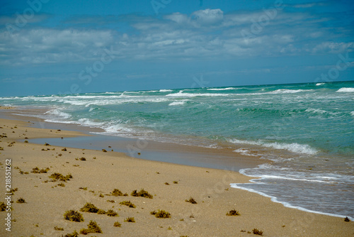 Beautiful sandy beach with waves and blue sky with clouds at New Smyrna Beach in Florida