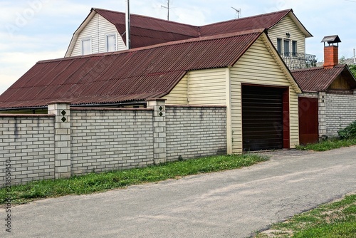 Fototapeta Naklejka Na Ścianę i Meble -  gray brick fence and brown garage outside on the road