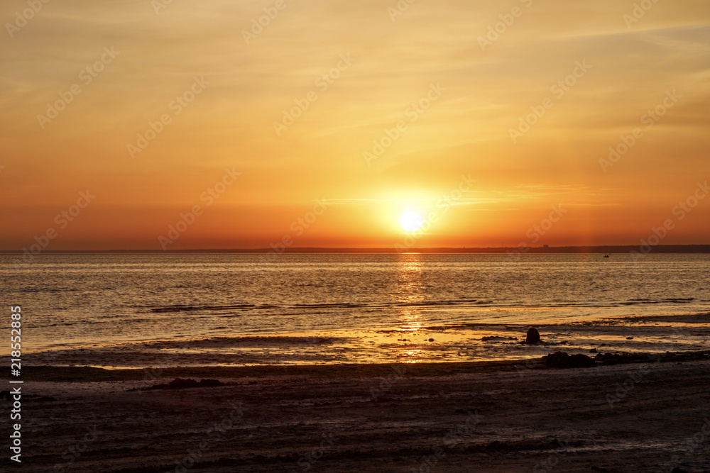 Obraz premium Beautiful sunset over the sea. The sun sets on the water. The sky is painted with golden bright colors. Summer evening. Sunset beach.
