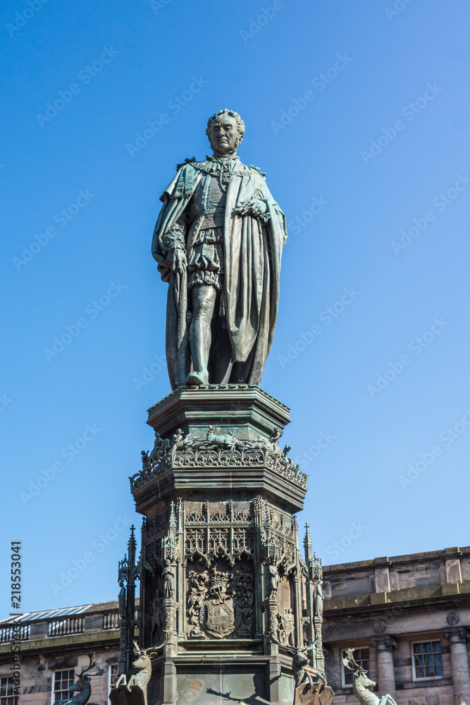 Edinburgh, Scotland, UK - June 13, 2012; Statue of Walter Montagu Douglas Scott, Duke of Buccleuch on Parliament Square against blue sky. Greenish bronze of man looking down on us. Deer images.