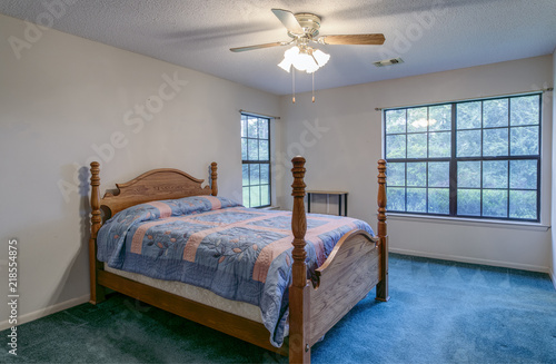 Interior of simple vintage 1980s bedroom with oak four post bed.