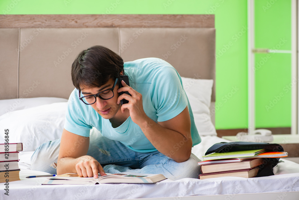 Student preparing for exams at home in bedroom sitting on the be Student preparing for exams at home in bedroom sitting on the be