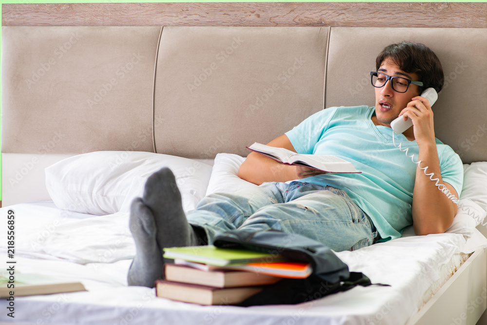 Obraz premium Student preparing for exams at home in bedroom lying on the bed