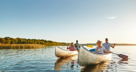 Smiling young friends canoeing together on a lake in summer