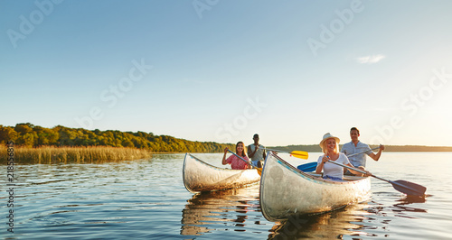 Smiling young friends canoeing together on a lake in summer