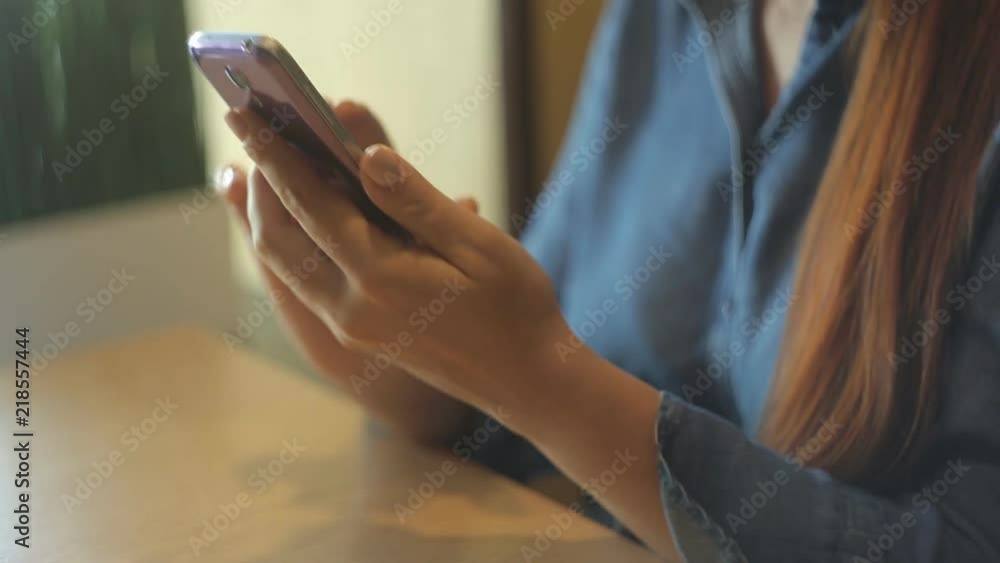 a beautiful Caucasian woman is a middle-aged businessman with red hair and glasses sitting with a smartphone in her hand in a cafe at a table. a beautiful Caucasian woman is a middle-aged businessman with red hair and glasses sitting with a smartphone in her hand in a cafe at a table.