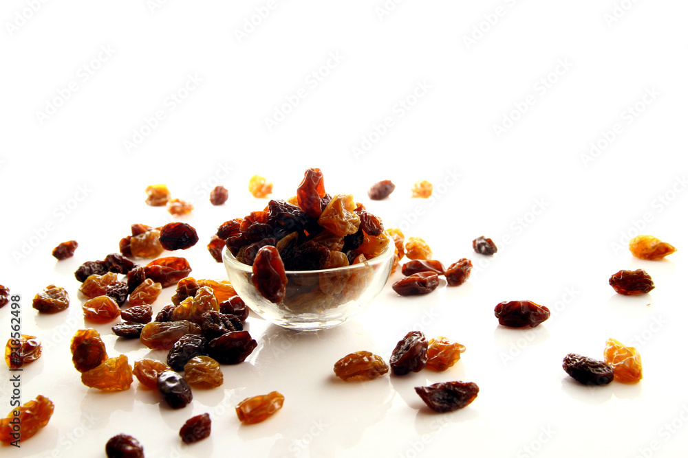 Fototapeta premium Raisins on white background / A raisin is a dried grape. Raisins are produced in many regions of the world and may be eaten raw or used in cooking, baking, and brewing