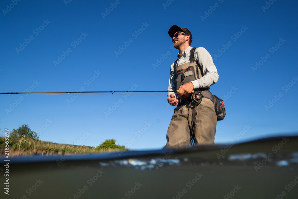 Over underwater shot of a man fly fishing in the summer in a river