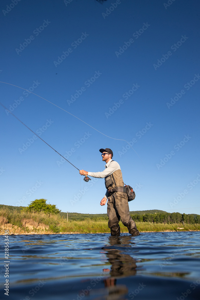 Over underwater shot of a man fly fishing in the summer in a river