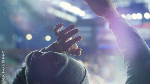 closeup hockey fan in cap holds hands put overhead and claps photo