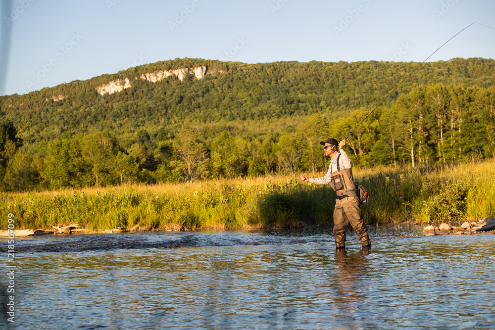 Man fly fishing in the summer in a river