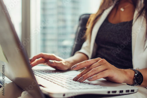 Close-up view of hands on keyboard woman using netbook sitting in office