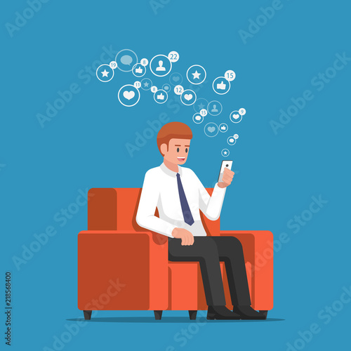 Businessman sitting at sofa and holding smartphone with social network notification icons