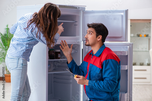 Man repairing fridge with customer