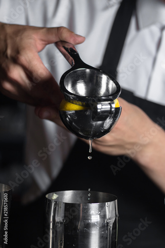 Barman squeezes lemon juice into a chilled shaker.
