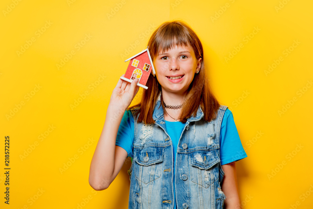 portrait of young teenage girl with toy house on yellow background portrait of young teenage girl with toy house on yellow background