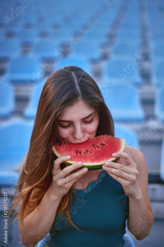 Girl eats watermelon on stadium
