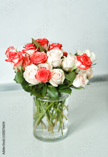 a bouquet of multi-colored roses stands in a glass vase on a white table in the kitchen © Olga